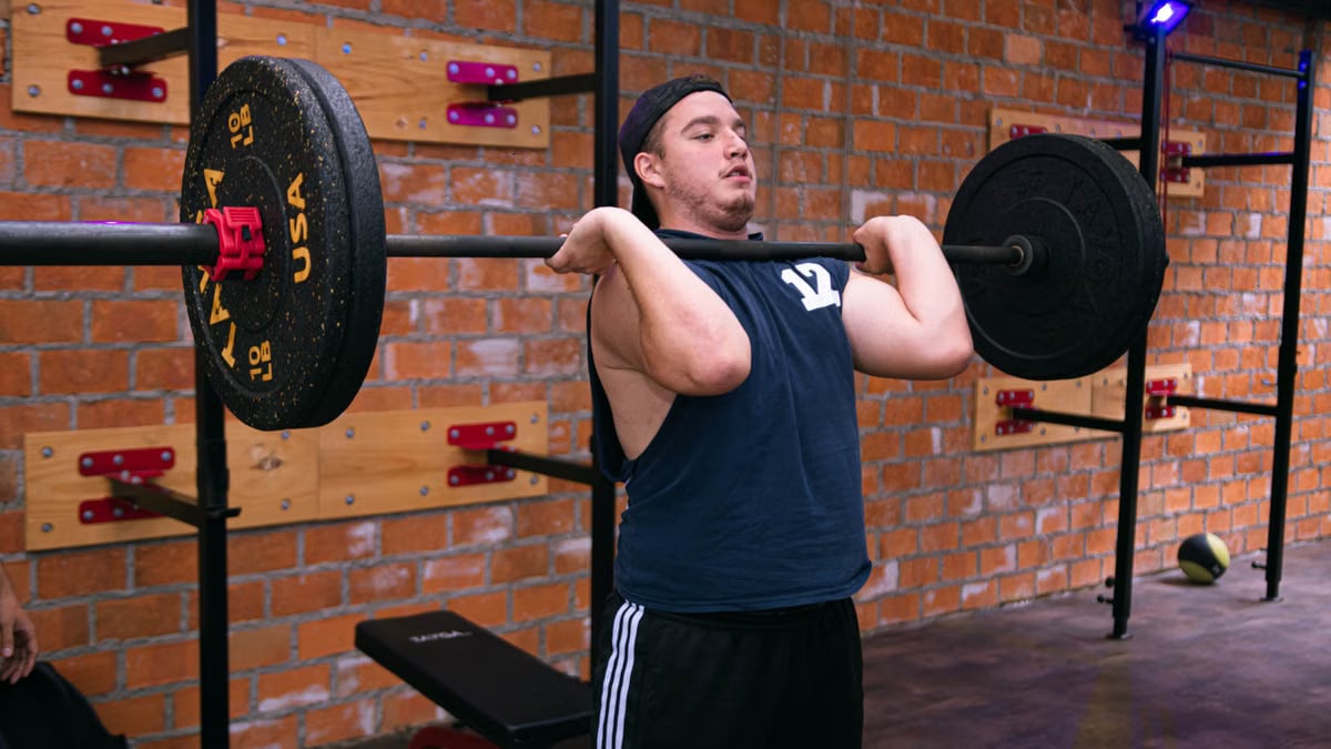 A man focuses on lifting a heavy barbell in a Ciudad de México gym.